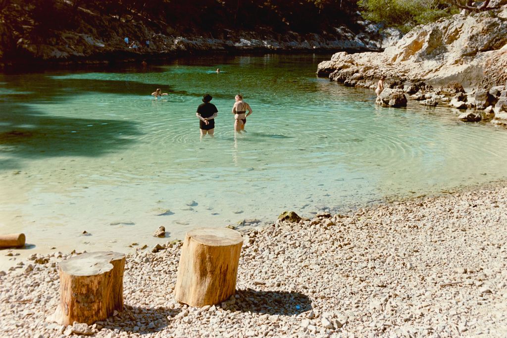 Baignade dans l'eau turquoise sur la plage de galets du Pont d'Arc