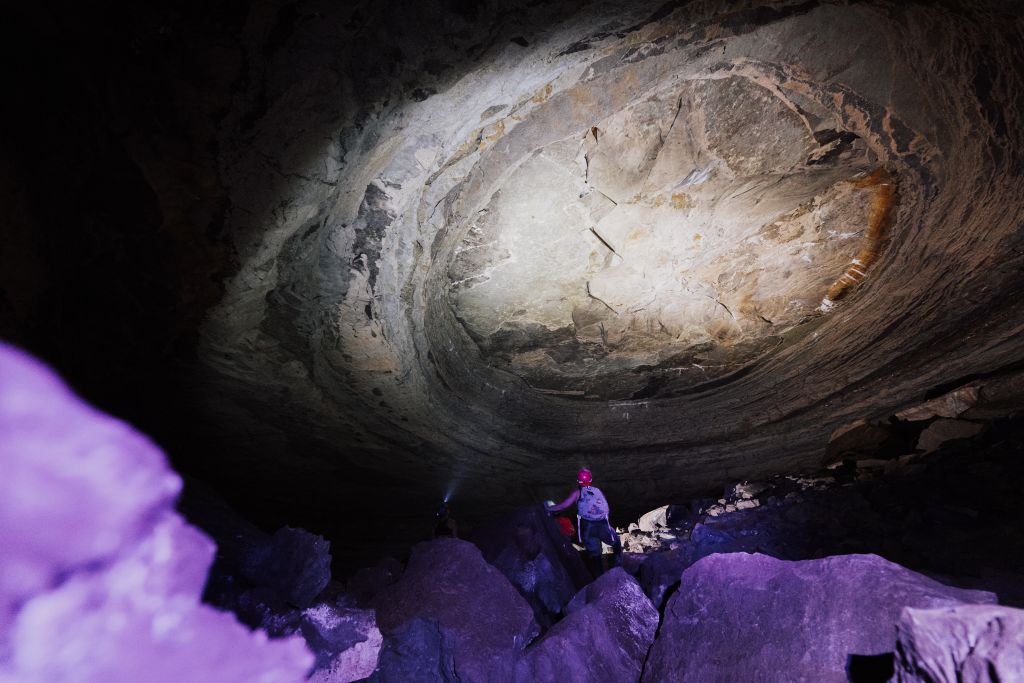 Grande salle d'une grotte sauvage éclairée à la frontale, le décor d'une sortie spéléologie en Ardèche du Sud