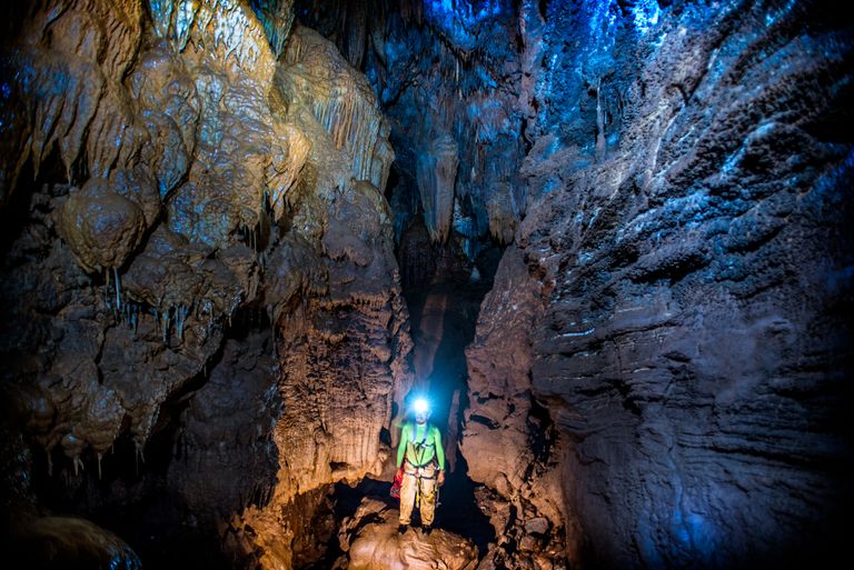 Spéléologue avec casque et lampe frontale dans une galerie de grotte sauvage, comme lors d'une initiation spéléo autour des Vans